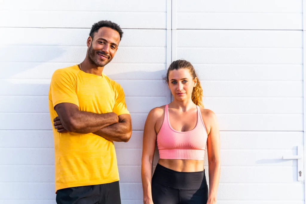 athletic man and woman posing by white wall utc